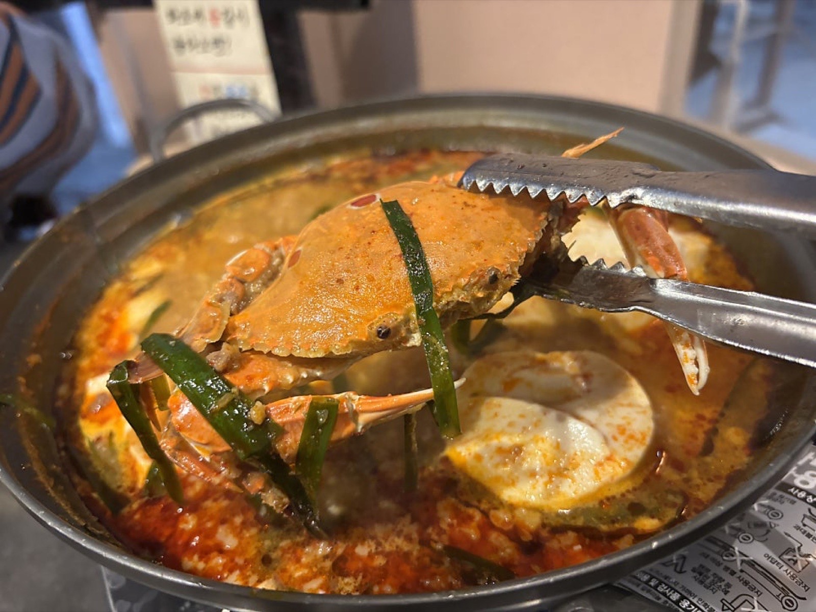 얼큰 꽃게 순두부전골에서 꽃게를 집게로 건져 올리는 모습