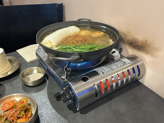 고기석 건대본점 얼큰 꽃게 순두부전골이 휴대용 버너 위에서 끓고 있는 모습