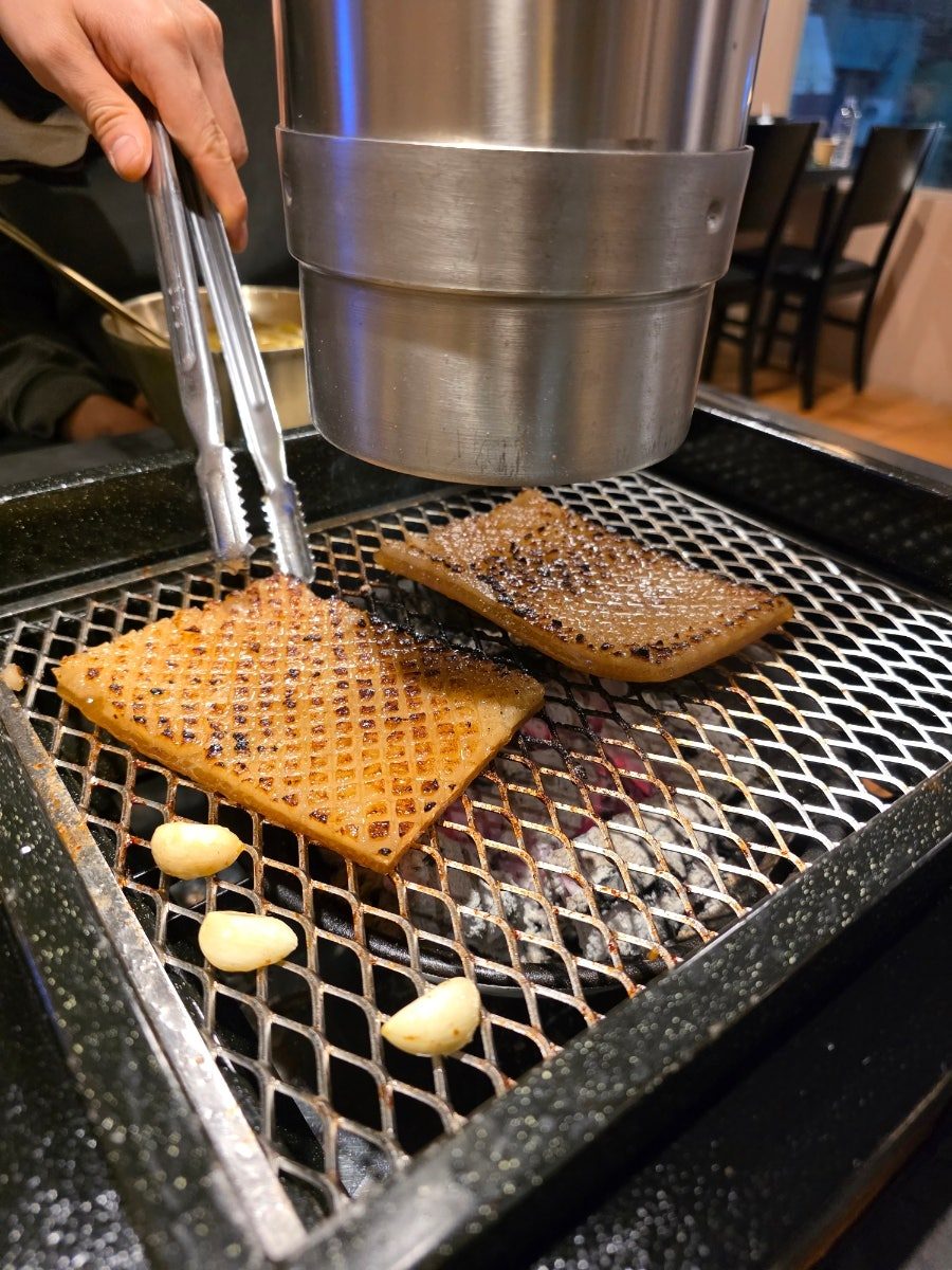 화로 위에서 칼집 낸 벌집 양념 돼지껍데기를 굽는 모습